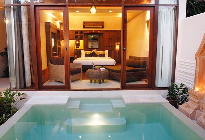 Montien House Hotel's gay-friendly room with private pool. Luxurious interior with wooden accents, comfy seating, and a king-size bed.