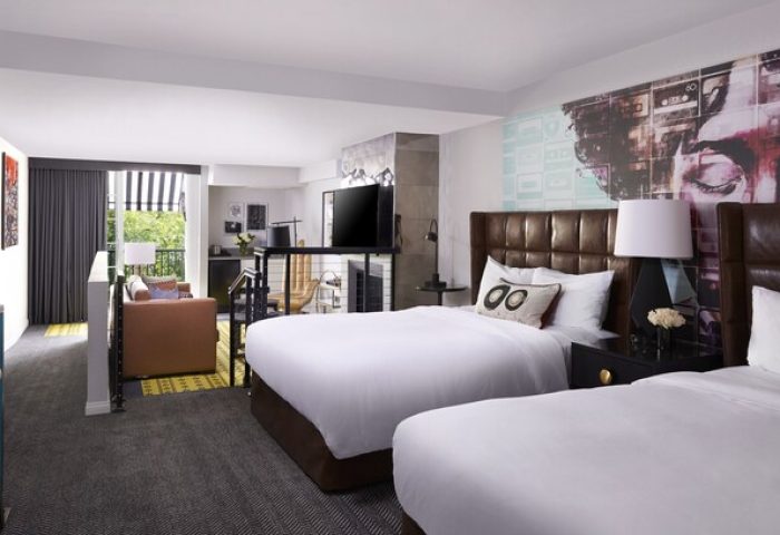 Montrose at Beverly Hills gay-friendly hotel room. Two beds with leather headboards, lounge area, balcony, and modern decor. Upscale travel.