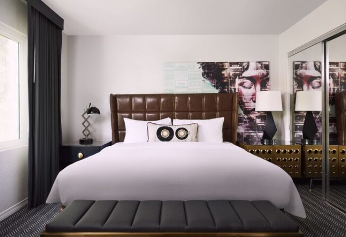 Bedroom at Montrose at Beverly Hills, a gay-friendly hotel. Features a bed, brown headboard, and modern art. Perfect for gay travel.