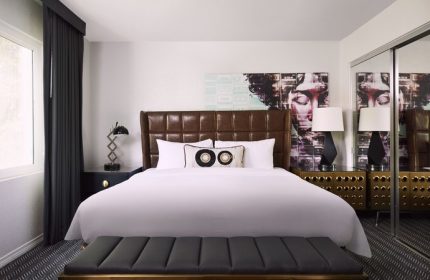 Bedroom at Montrose at Beverly Hills, a gay-friendly hotel. Features a bed, brown headboard, and modern art. Perfect for gay travel.