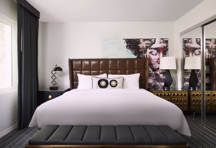 Bedroom at Montrose at Beverly Hills, a gay-friendly hotel. Features a bed, brown headboard, and modern art. Perfect for gay travel.