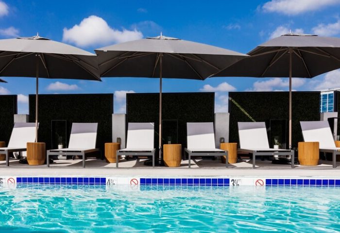 Poolside at Montrose at Beverly Hills, a gay-friendly hotel. Lounge chairs and umbrellas offer relaxation under a blue sky. Perfect for gay travel.