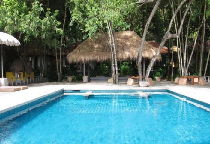 Pool at Gay-Friendly Mooban Talay Resort. Tropical getaway with lush greenery, thatched roof gazebo, and inviting blue water.