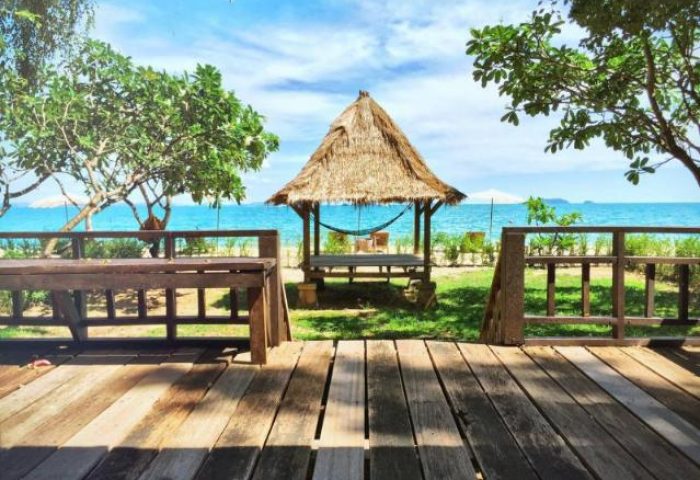 Mooban Talay Resort, a gay-friendly hotel. Thatched hut with hammock on a beach. Wooden deck and ocean view. Tropical gay travel.