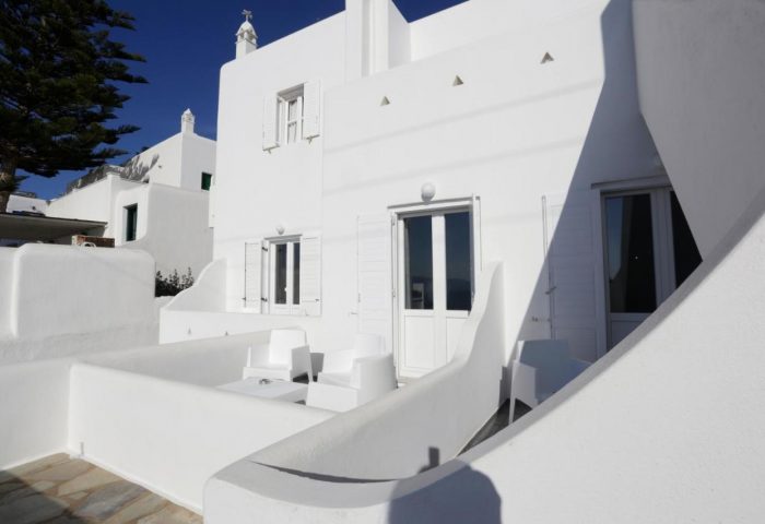 Morfoula's Studios: White exterior of a gay-friendly hotel. Balcony with chairs and table. Traditional Greek architecture. Ideal gay travel.