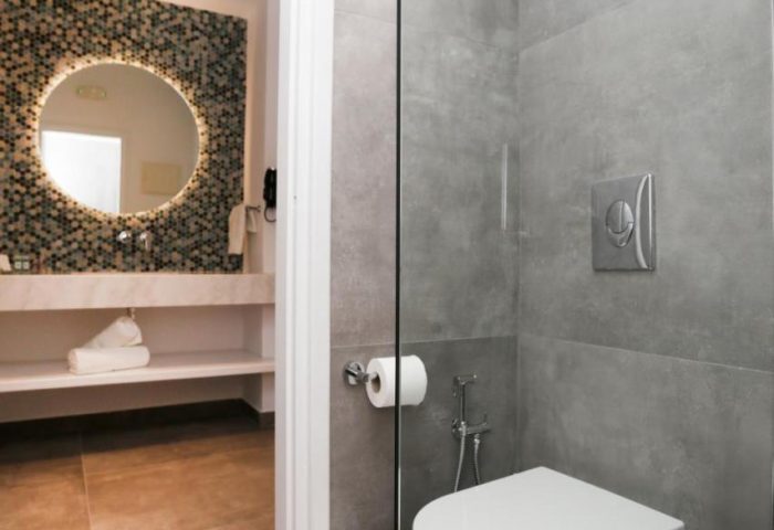 Bathroom at Morfoulas Studios, a gay-friendly hotel. Toilet, sink, and mirror visible. Modern design for gay men's travel.