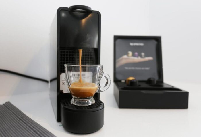 Coffee machine at Morfoulas Studios, a gay-friendly hotel. Espresso pours into a glass cup. Pods are in a box. Enjoy your stay!