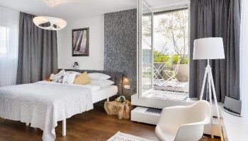 Mosaic House Design Hotel bedroom with balcony. Gay-friendly hotel room featuring a bed, chair, and outdoor space. Modern interior design.