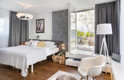 Mosaic House Design Hotel bedroom with balcony. Gay-friendly hotel room featuring a bed, chair, and outdoor space. Modern interior design.
