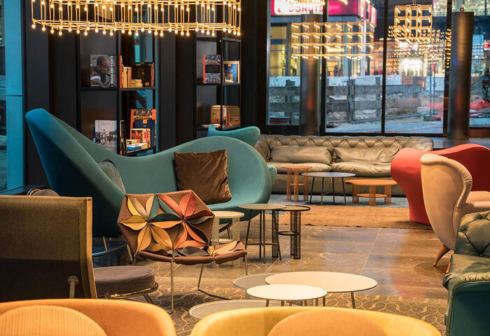 Lobby seating area at Motel One Berlin-Alexanderplatz, a gay-friendly hotel. Modern decor with stylish chairs and couches. Interior design.
