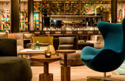 Motel One Koln-Neumarkt's gay-friendly hotel interior. A stylish bar area with colorful decor, seating, and a fully stocked bar. Cologne, Germany.