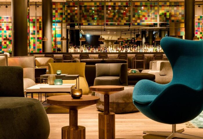 Motel One Koln-Neumarkt's gay-friendly hotel interior. A stylish bar area with colorful decor, seating, and a fully stocked bar. Cologne, Germany.