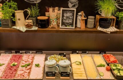 Breakfast buffet at Motel One Koln-Neumarkt, a gay-friendly hotel. Selection of cold cuts, cheese, and fresh produce. Coffee and herbs.