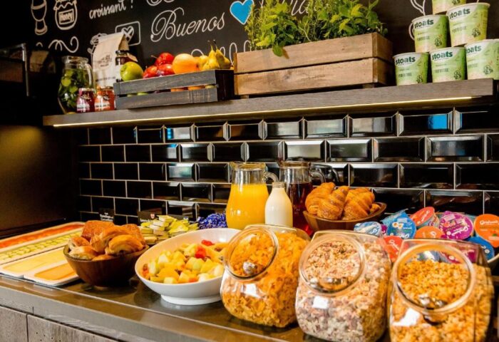 Breakfast buffet at the gay-friendly Motel One London - Tower Hill. Cereal, fruit, pastries, juice, and other options are available.