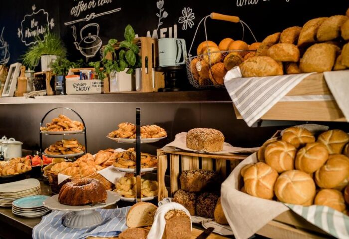 Breakfast buffet at Motel One London-Tower Hill, a gay-friendly hotel. Variety of breads, pastries, and fruits on display.