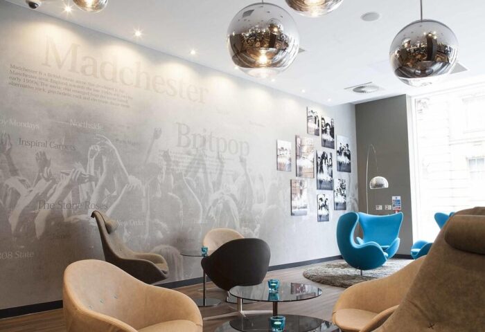 Motel One Manchester-Piccadilly's stylish lobby. Gay-friendly hotel with modern decor, accent chairs, and Manchester music-themed wall art. Disco balls.
