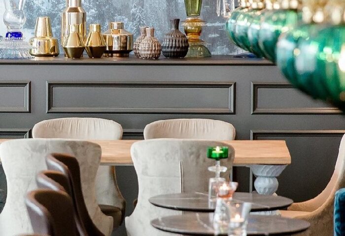 Motel One München Sendlinger Tor interior. Gay-friendly hotel with chandeliers, castle mural, tables, and chairs. Upscale design.