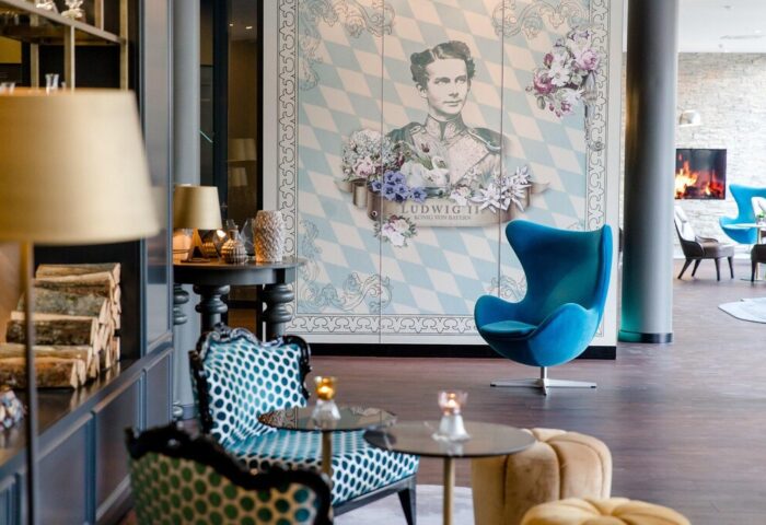 Motel One München Sendlinger Tor lobby with Ludwig II portrait. Gay-friendly hotel with modern design and cozy seating. Perfect for LGBTQ+ travelers.