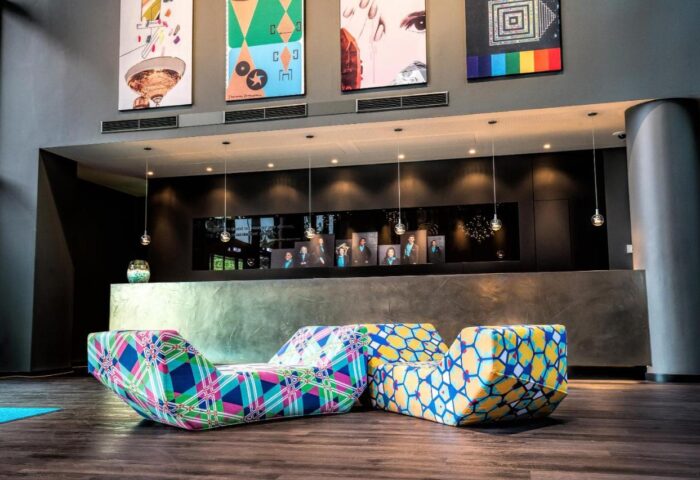 Motel One Wien Westbahnhof lobby. Gay-friendly hotel with colorful furniture, modern art, and sleek reception. Vienna travel advice.