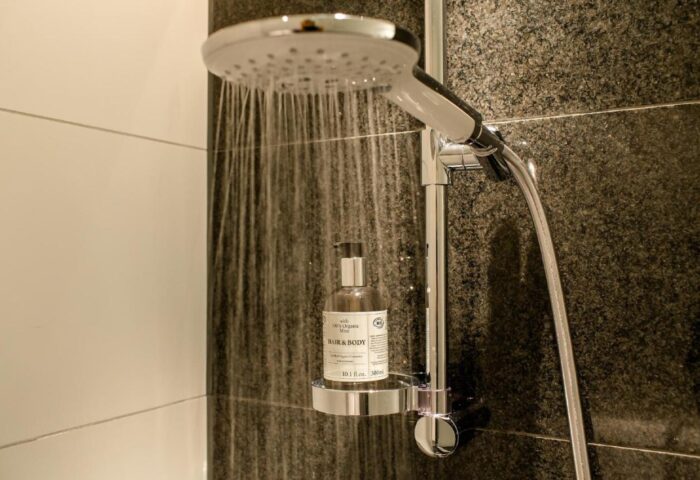 Shower detail at Motel One Wien Westbahnhof, a gay-friendly hotel. Modern bathroom with rain shower head and organic hair & body product.
