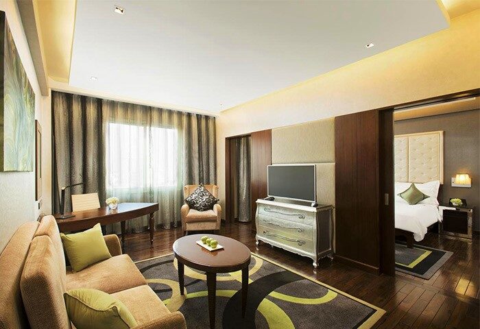 Mövenpick Hotel Hanoi suite. Gay-friendly hotel room with living area, desk, TV, and bedroom. Ideal for gay travelers seeking comfort.