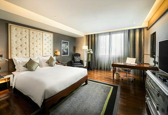 Movenpick Hotel Hanoi gay-friendly room. A luxurious bed, desk, and chair offer comfort. Perfect for gay travelers seeking style.