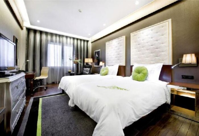Movenpick Hotel Hanoi gay-friendly room. Two beds with white linens, green pillows, desk, TV. Luxury hotel for gay travelers in Hanoi.
