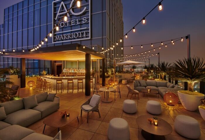 Rooftop bar at the gay-friendly Moxy Downtown Los Angeles hotel. String lights, seating areas, and a bar create a stylish, inviting space.