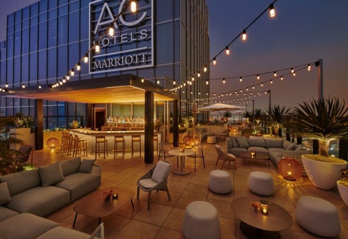 Rooftop bar at the gay-friendly Moxy Downtown Los Angeles hotel. String lights, seating areas, and a bar create a stylish, inviting space.