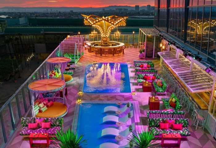 Rooftop pool and bar at the gay-friendly Moxy Downtown Los Angeles hotel. Stylish seating areas and city views. Vibrant, inclusive travel destination.