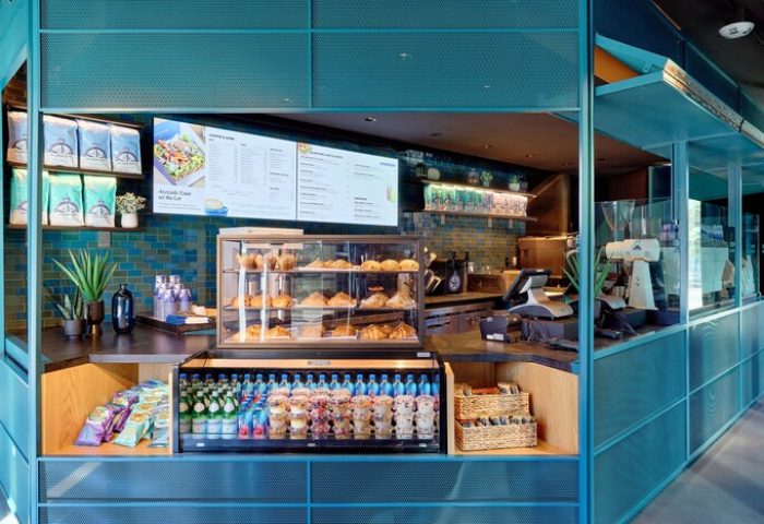 Moxy Downtown Los Angeles gay-friendly hotel cafe. Turquoise design with pastries, drinks, and snacks. Menu board above the display case.
