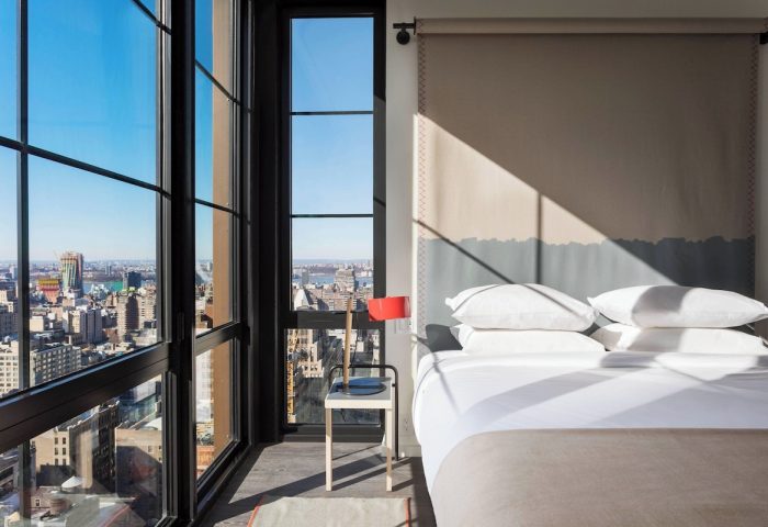 Moxy NYC Chelsea hotel room with skyline view. Gay-friendly hotel with modern design, large windows, and comfortable bed. Perfect for gay travel.