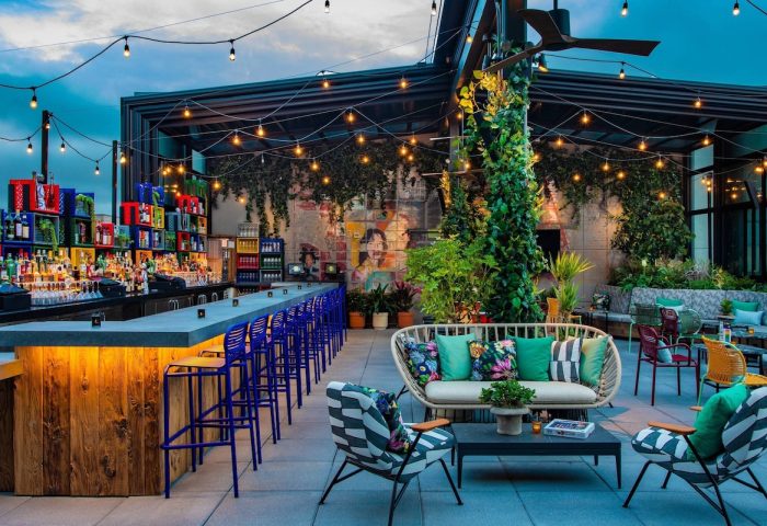 Rooftop bar at the gay-friendly Moxy NYC East Village hotel. Outdoor seating, string lights, and colorful decor create a vibrant, welcoming atmosphere.