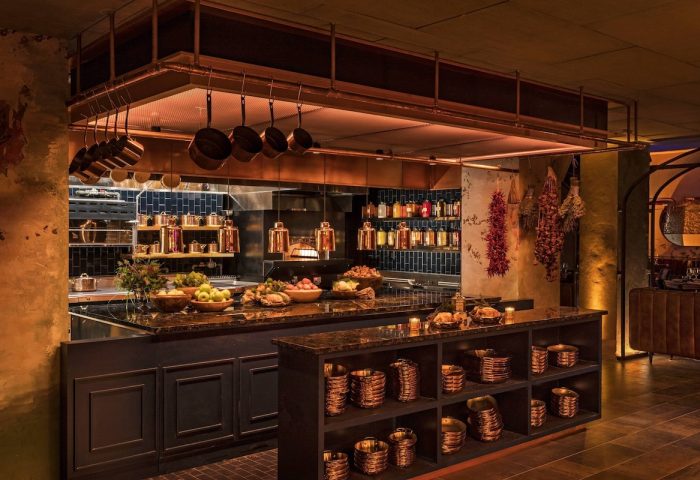 Moxy NYC East Village's kitchen. Copper pots hang above the counter. Shelves display copper bowls. A gay-friendly hotel with unique design.