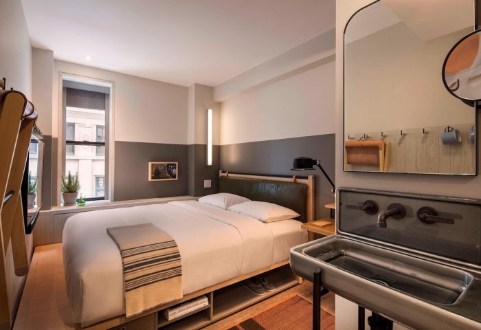 Moxy NYC Times Square hotel room. Gay-friendly hotel with bed, unique sink, and city view. Great for gay men travel in New York City.