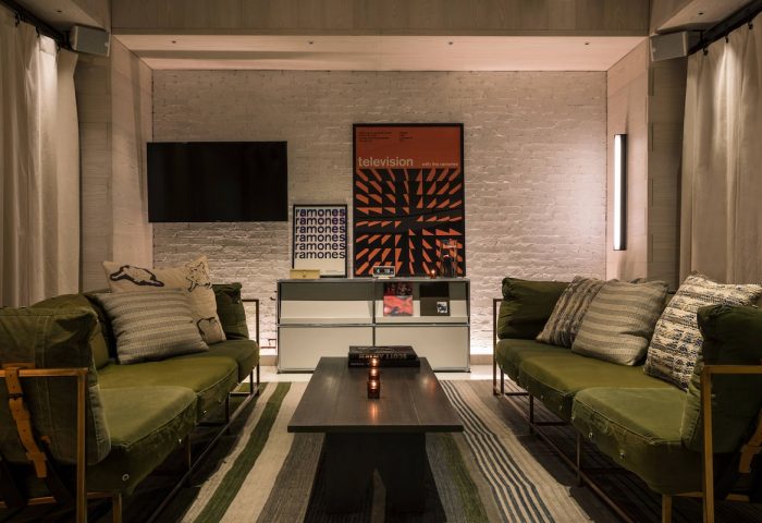 Moxy NYC Times Square hotel lounge area. Two green sofas face each other. Gay-friendly lodging with modern design. NYC travel advice.