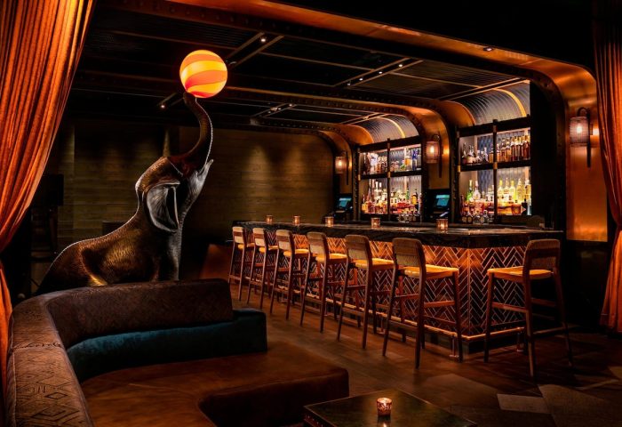 Moxy NYC Times Square bar area. Elephant statue with a ball on its trunk. Gay-friendly hotel with unique design elements. Interior view.