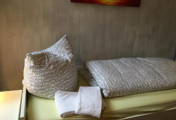 My Gayhostel room: Bed with patterned linens, pillow, and towels. A gay-friendly hotel offering comfortable accommodations for gay men travel.