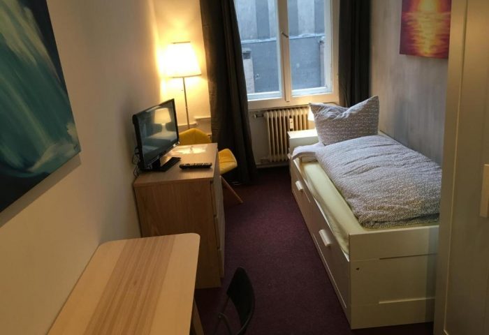My Gayhostel room. Gay-friendly hotel room with single bed, desk, TV, and window. A cozy space for gay travelers.