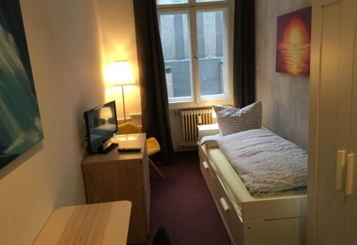 My Gayhostel room: Cozy single bed, TV, and window. A gay-friendly hotel offering comfortable accommodations for gay travelers.