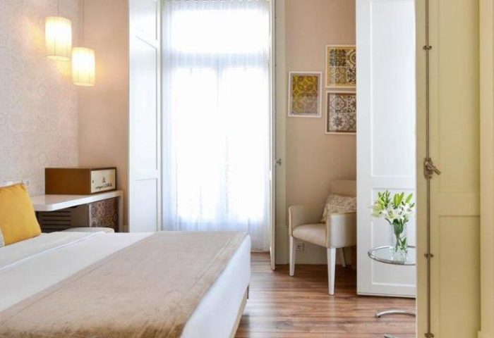 My Story Hotel Ouro room: Gay-friendly hotel bedroom with double bed, chair, flowers, and patterned wall art. Ideal for gay men's travel in Lisbon.