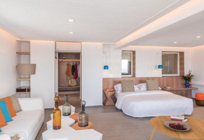 Myconian Korali Relais & Chateaux gay-friendly hotel room. Modern design with white walls, bed, sofa, and unique decorative elements.