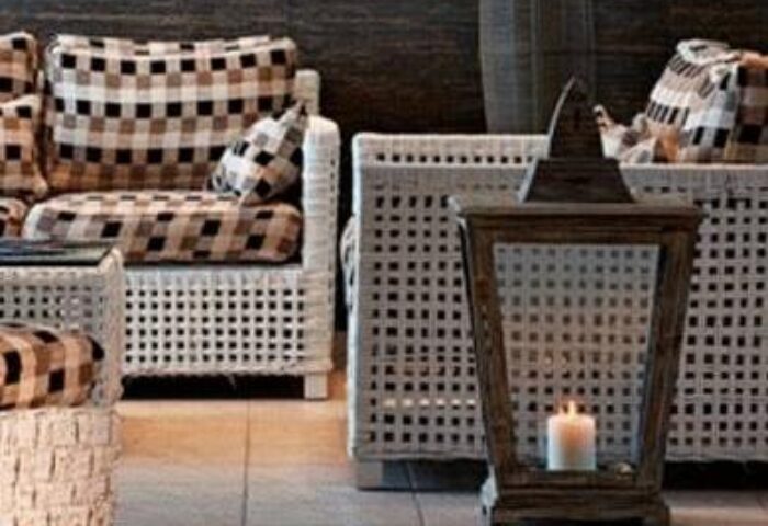 Myconian Korali Relais & Chateaux detail: Wicker furniture with checkered cushions, wooden lantern with candle. Gay-friendly hotel interior.