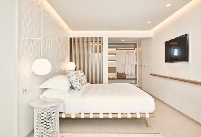 Myconian Kyma Design Hotel's bright, modern room. This gay-friendly hotel features a bed, closet, and TV. Minimalist design.
