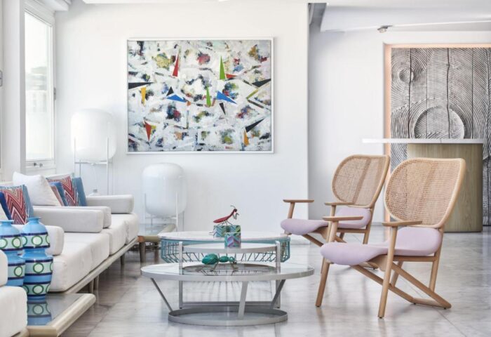 Myconian Kyma Design Hotel's stylish lounge area. Gay-friendly hotel interior with modern art, wicker chairs, & chic decor. Mykonos travel.