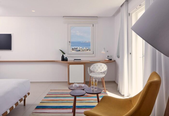 Myconian Kyma Design Hotel room. Gay-friendly hotel room interior with desk, chair, and sea view. Modern design in Mykonos, Greece.