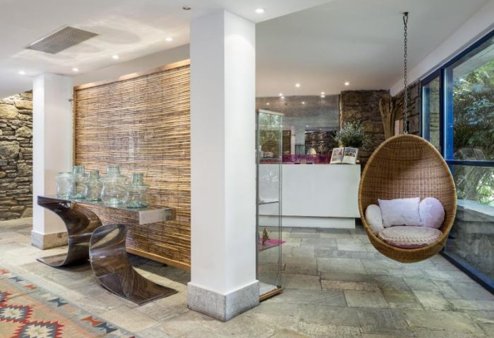 Mykonos Theoxenia hotel lobby with hanging chair, vases, stone walls, and modern design. Gay-friendly hotel for gay men's travel in Mykonos.