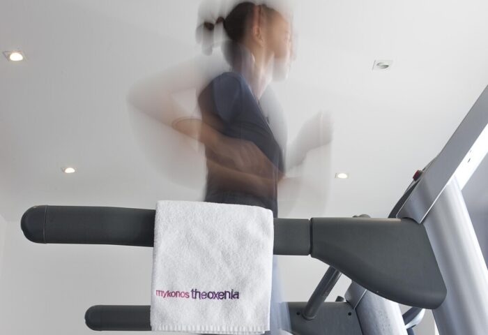 Gay-Friendly Hotel Mykonos Theoxenia: Person running on a treadmill. Towel with mykonos theoxenia logo. Gym facilities at hotel.