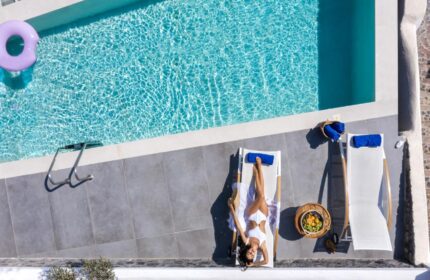 Mythical Blue Luxury Suites pool view. Woman relaxing on a sunbed. Gay-friendly hotel pool scene. Vacation goals.