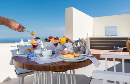 Breakfast at Mythical Blue Luxury Suites, a gay-friendly hotel. Honey being poured over fruit and yogurt. Ocean view. Santorini luxury.